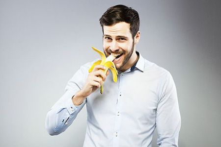 мужчина ест банан