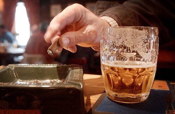 стакан алкоголя на столе и сигарета в руке мужчины